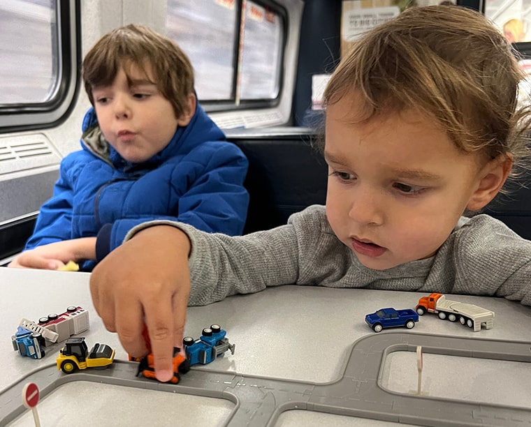 boys playing with trucks on train