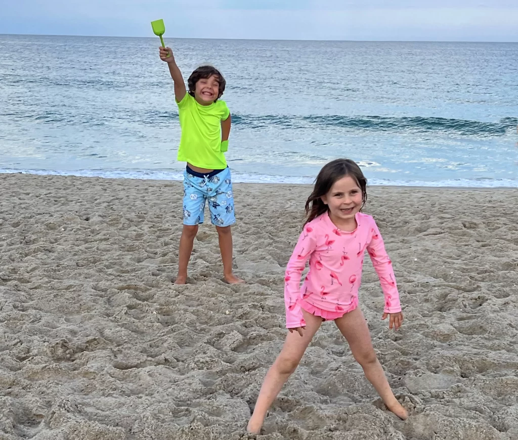 a young boy and girl playing on the beach