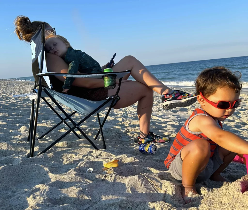 a mom with two young children on the beach relaxing in the sand