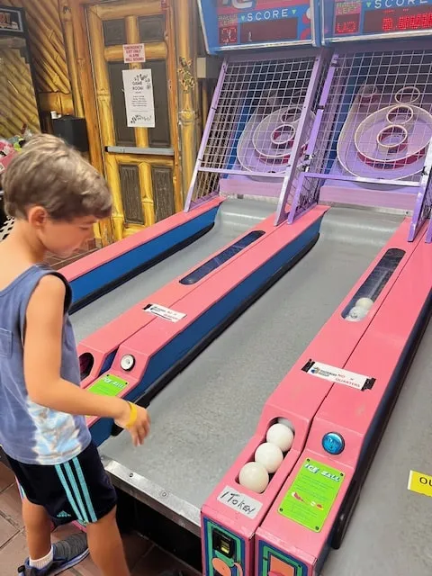 little boy playing skee ball arcade game