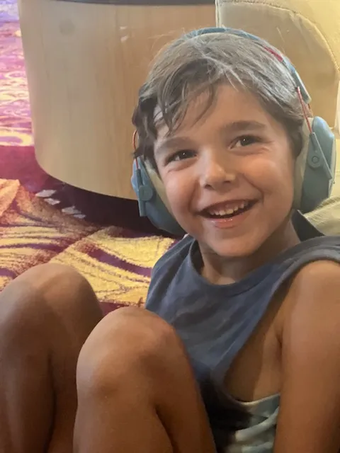 A happy and smiling boy wearing headphones and a tank top.