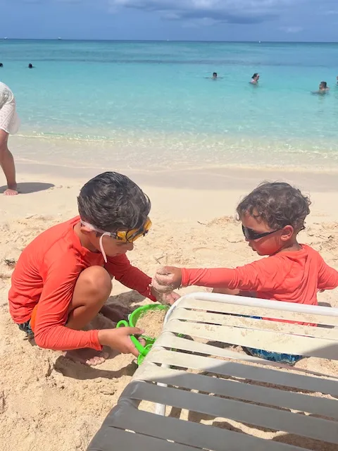 Two boys playing in the sand at beach on a sunny day.