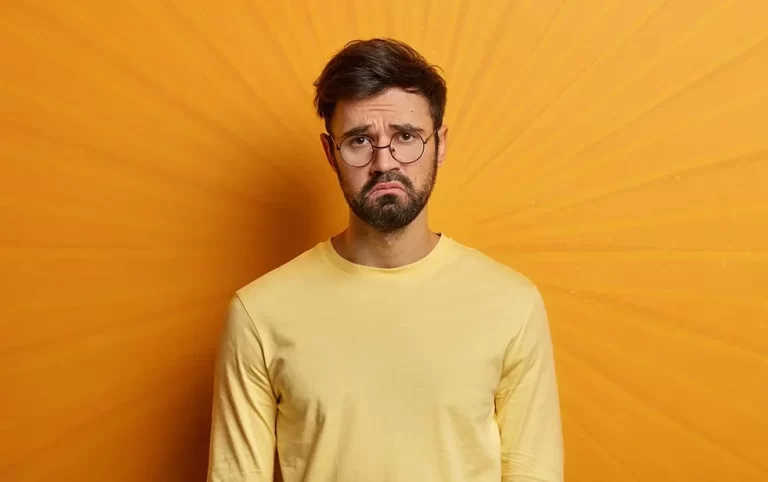 An unhappy young dad wearing glasses and yellow shirt frowning.