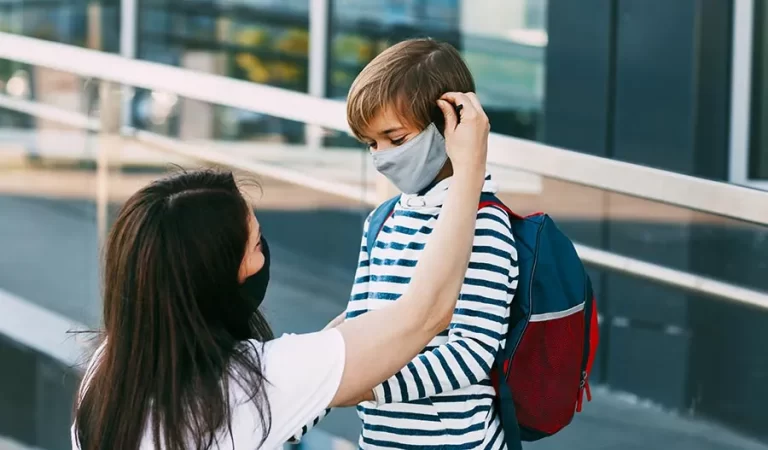 Mother adjusts her sons face mask.