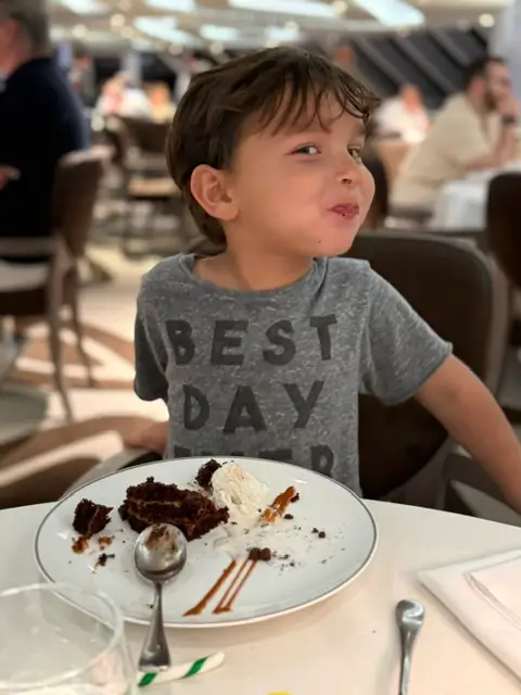 A young boy enjoying a chocolate dessert at a restaurant table in the MSC Yacht Club dining room.