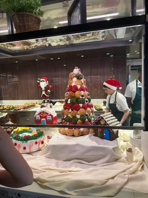 Festive holiday dessert display featuring a croquembouche tree, gingerbread houses, and Santa figures.